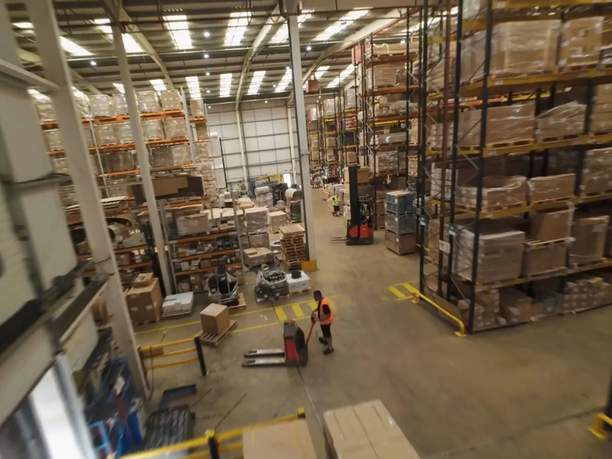 FPV fly-through of a warehouse with racking and a forklift