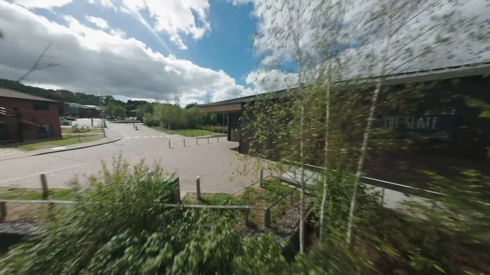 FPV drone reveal flying over trees towards a modern building